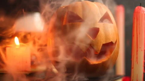 Steaming head Halloween Jack pumpkin on the table near a glass with smoke Stock Footage 68417022
