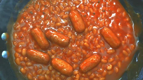 Steaming hot baked beans and pork sausages in tomato sauce, in a pan. Stock-Footage 257086826