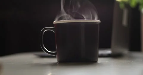 Steaming hot beverage in a dark mug on a reflective surface Stock Footage 339072494