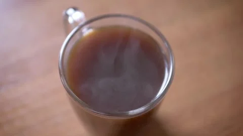 Steaming Hot Black Coffee in a Clear Glass Mug on a Wooden Table Stock-Footage 339067216