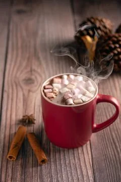 Steaming hot chocolate with marshmallows in red mug on wooden surface with Stock Photos