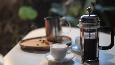 Steaming hot coffee in a cup and French press on a table with coffee beans Stock Footage 338990583