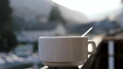 Steaming hot coffee cup on balcony railing Video stock 323181833