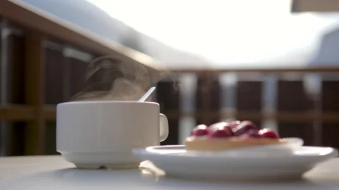 Steaming hot coffee cup with a fruit tart on table at terrace Stock Footage 320945317