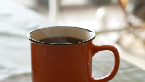 Steaming Hot Coffee in Orange Mug with Warm Morning Light Stock Footage 318335501