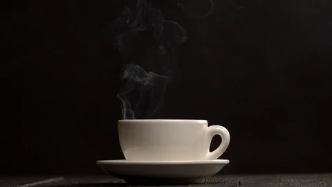 Steaming hot cup of coffee. Steam coming from a white coffee cup on a black Stock-Footage 100287090