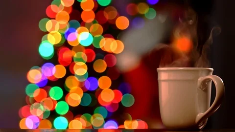 A steaming hot drink with Christmas lights and stocking hung by the fireplace Stock Footage 119889593