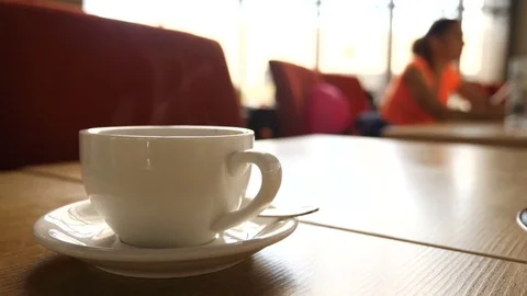 A steaming hot mug of coffee with blurred people moving in the background. Stock Footage