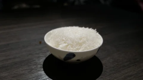 Steaming hot rice in a white bow with blue flower, on top of a dark wooden table Vídeos de archivo 90763641