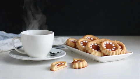 Steaming hot tea in white cup and homemade cookies on the plate Stock Footage 149411759