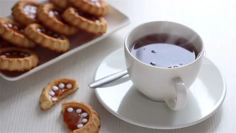 Steaming hot tea in white cup and homemade cookies top view close up Stock Footage 190773690