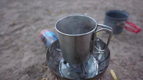 Steaming Metal Cup Heating Water on Portable Camping Stove Outdoors Stock Footage 341994551