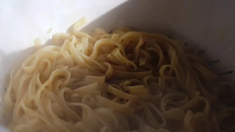 Steaming pasta draining in white colander, hot water vapor rising, highlighting Vidéo 309050240