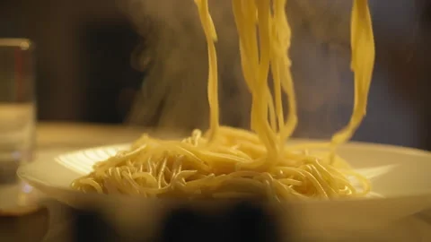 Steaming plate of pasta being served in a cozy dining setting during dinner Stock Footage 301407805