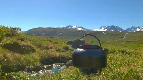 Steaming tea kettle in mountain terrain in Norway Stock Footage 156789184