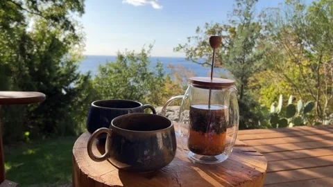 Steaming tea poured into rustic mugs on a wooden table during an outdoor breakfa Stock Footage 304879551