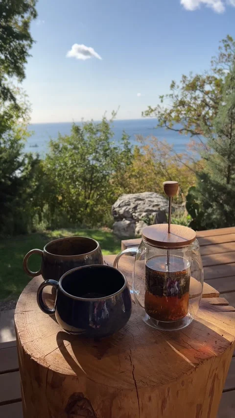 Steaming tea poured into rustic mugs on a wooden table during an outdoor breakfa Stock Footage 304879610