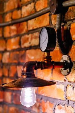 Steampunk style interior design close up lamp and manometer over red brick wall Stock Photos