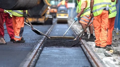 Steamroller workers construct asphalt road and railroad lines Stock Footage 79497159