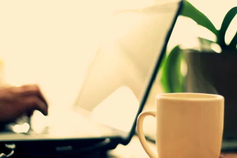 Steamy cup of coffee or tea with man working on laptop in background Stock Footage 949289