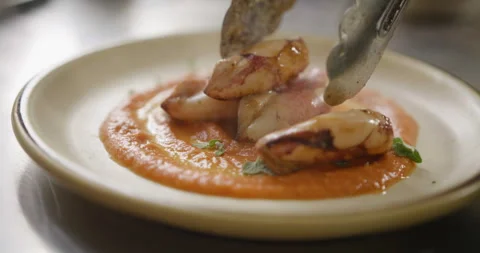 Steamy hot fried squid placed on sauce-decorated plate by tongs Stock Footage 274653516
