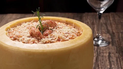 Steamy Italian shrimp risotto served inside a big Parmesan Cheese Wheel Stock Footage 119046643