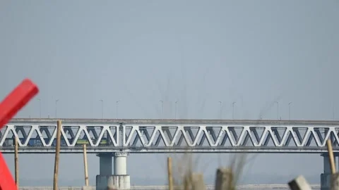 Steel bridge with geometric pattern and distant train in motion Vídeos de archivo 331277123