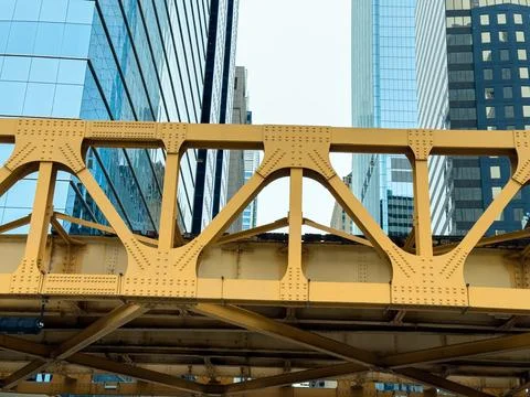 Steel bridge structure stands between tall buildings in a city skyline duri.. Stock Photos