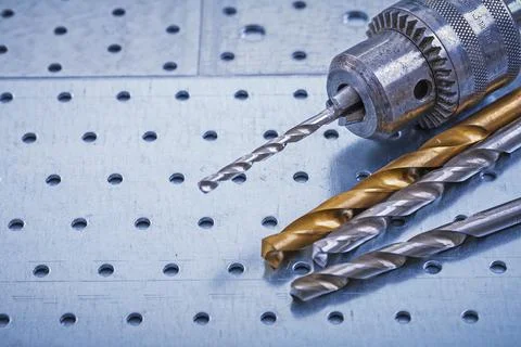 Steel drill with boring bits on perforated metallic background construction Stock Photos