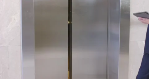 Steel elevator doors are opening, revealing nurse with tablet and speaking to Stock Footage 336784437