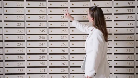 Steel mailboxes in an apartment building. Rows of numbered mailboxes. A woman Vídeo Stock 239672437