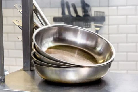 Steel pans are a stack on the shelf in the kitchen of the restaurant. Stock Photos