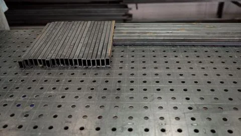 Steel rectangular tubes on a perforated welding table in a metal workshop Stock Photos