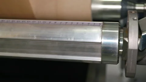 A steel roller with a measuring unit rotates on a calender. Stock Footage 163066054