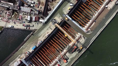 Steel sheet piles stack neatly at Antwerp port construction site, yellow crane Stock Footage 348251686