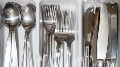 Steel silverware spoon, fork and knife piled in a drawer. Stock Photos