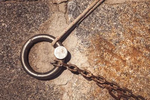 Steel solid ring and mooring lines in a seaport. Rusty iron chain and hemp ro Stock Photos