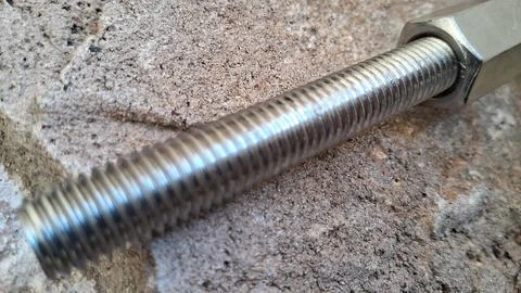Steel threaded bolt on stone background. Industrial metal fastener for Stock Photos