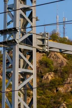 Steel tower structure with electrical cables and rocky hill background at s.. Stock Photos