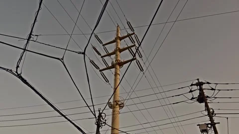 Steel Utility Pole and Tangled Overhead Power Lines Against Flat Gray Sky, Japan Stock Footage 337975538