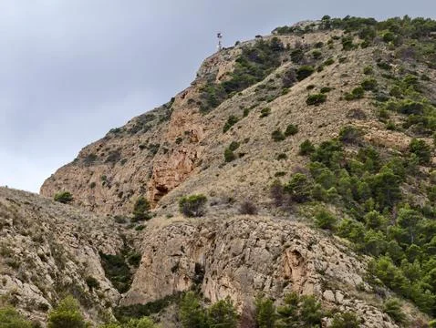 Steep cliff featuring summit marker and cave, sharp cliffside with summit marker Foto stock