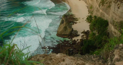 Steep cliff overlooks turquoise ocean waves at Diamond Beach in Nusa Penida Bali Stock Footage 344701950