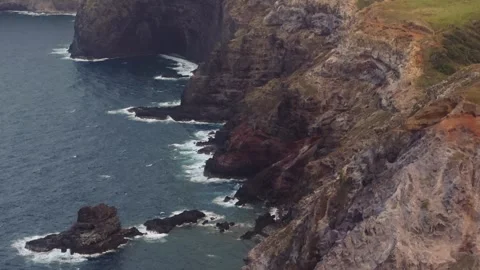 Steep eroded escarpment cliffs drop off into black sand beach on North Stock Footage 276109447