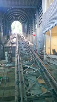 Steep funicular railway tracks inside a tunnel structure lead upward into daylig Stock Photos