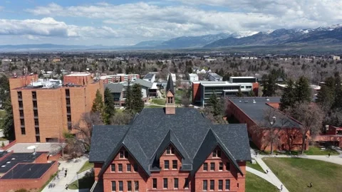 Steep gabled roofline and spire crown historic university hall, students Stock Footage 337747555