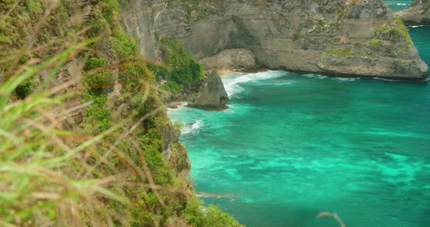 Steep Green Cliffs Meet Bright Turquoise Water At Diamond Beach in Nusa Penida Stock Footage 341356828