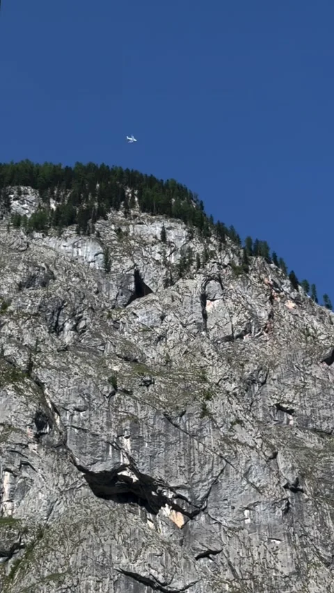 Steep grey rock cliff face against deep blue sky Berchtesgaden Stockbeeldmateriaal 341768912
