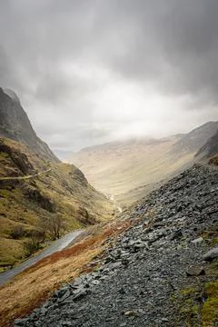 Steep mountain pass and rugged terrain under moody skies in Honister Pass Stock Photos