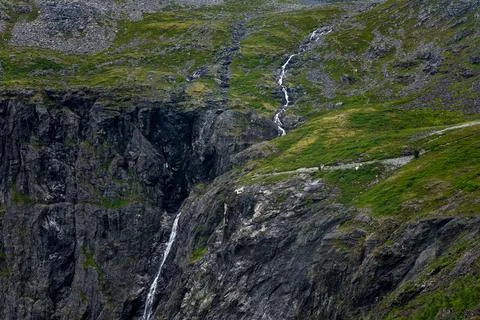 Steep mountain slope with multiple white waterfalls descending dark rock face Stock Photos