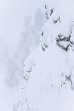 Steep mountain slope in the shape of huge monkey head in a snowstorm in winter Stock Photos